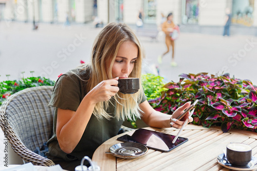 A woman with smiley face holding and using Ipad tablet pc while drinking coffee in modern cafe