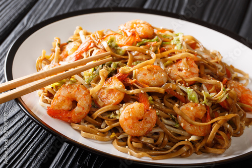 Stir fried chow mein noodles with shrimp  vegetables and sesame seeds close-up on the table. horizontal
