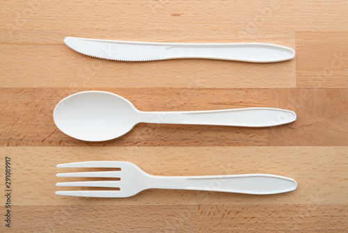Biodegradable plastic spoon, fork and knife made from starch on wooden background
