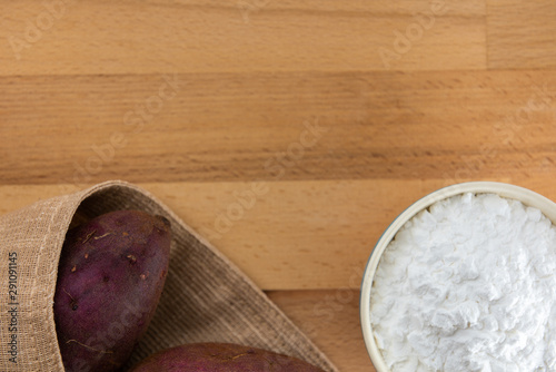 Top view of sweet potato starch in white bowl with sweet potato wooden table background