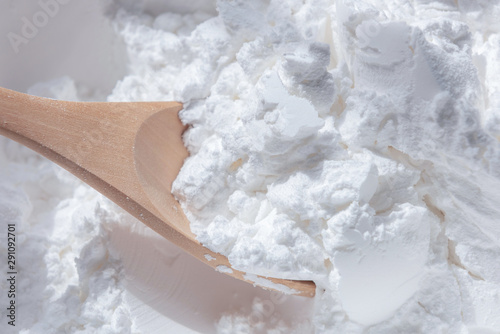 Close-up of tapioca starch or flour powder in wooden spoon on white background