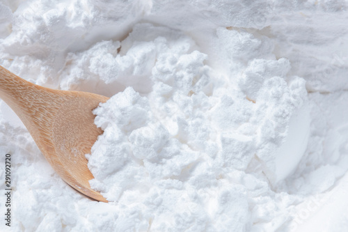 Close-up of tapioca starch or flour powder in wooden spoon on white background