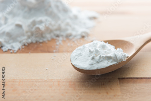 Close-up of tapioca starch or flour powder in wooden spoon with wooden background