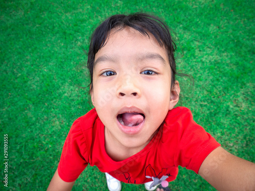 Asia kid girl smiling playing in the field, Happy and Stick out tongue, looking to camera.
