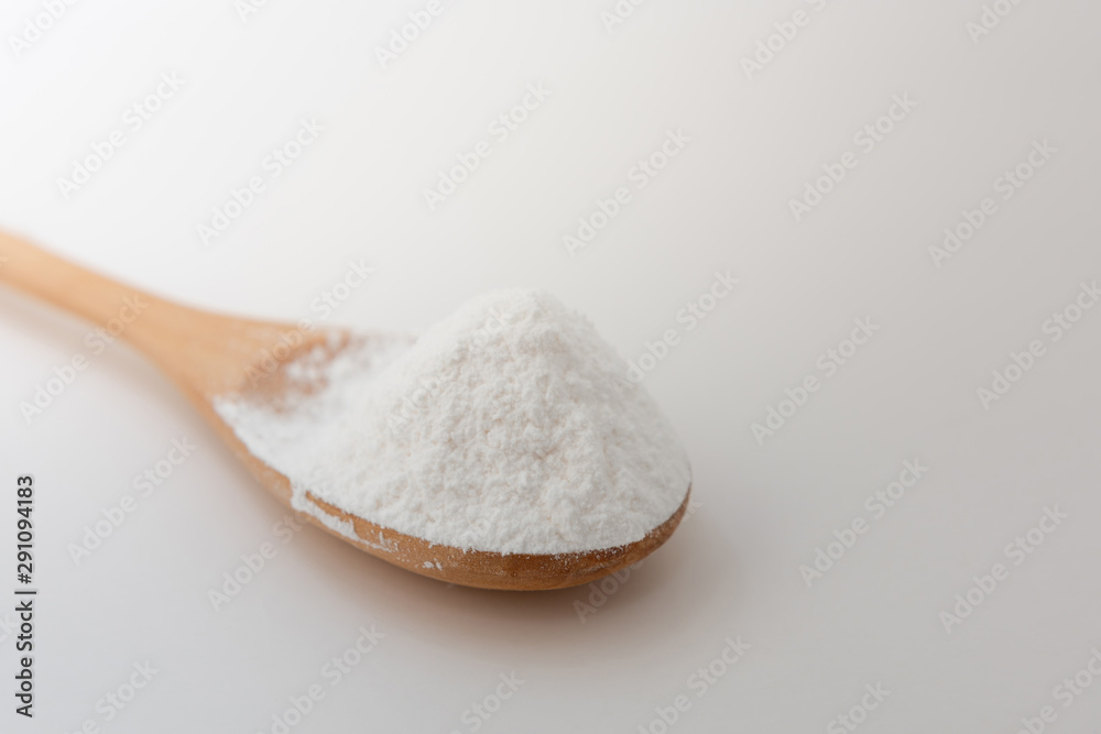 Close-up of tapioca starch or flour powder in wooden spoon with white background isolated
