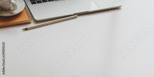 Minimal comfortable workplace with laptop computer and coffee cup on white table
