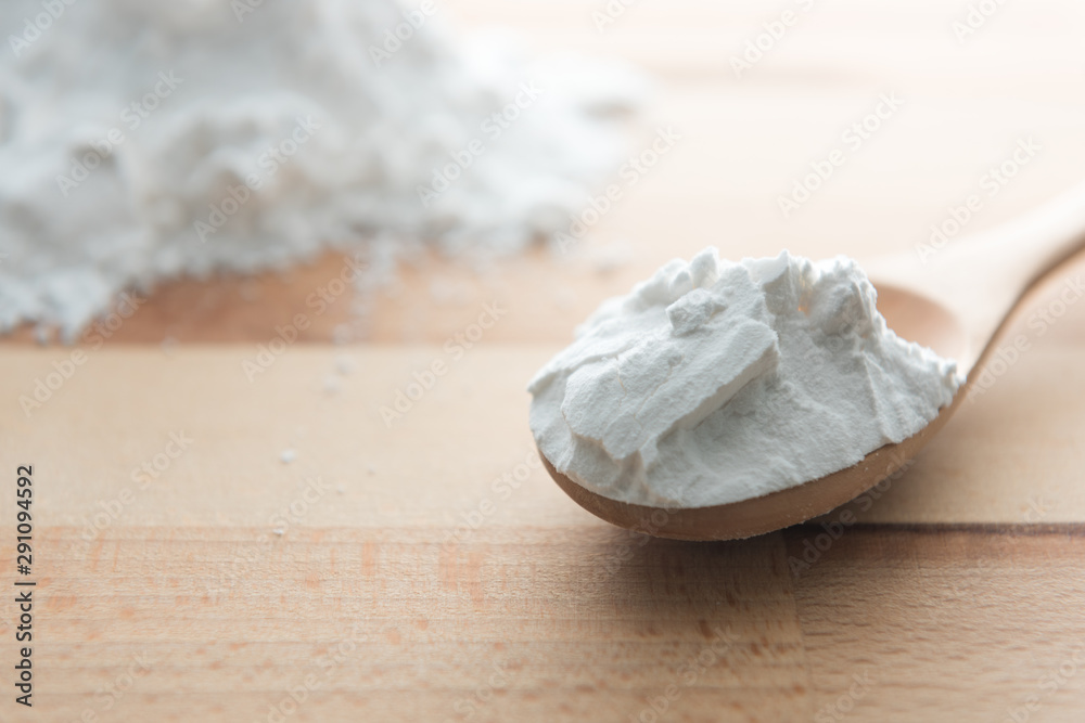 Close-up of tapioca starch or flour powder in wooden spoon on white background Close-up of tapioca starch or flour powder in wooden spoon on white background