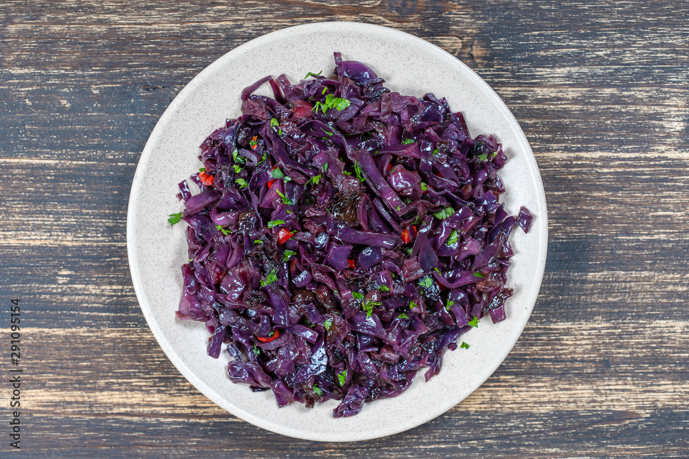 Fried blue cabbage with onion, apple and garlic in plate on wooden table. Top view, closeup Fried blue cabbage with onion, apple and garlic in plate on wooden table. Top view, closeup