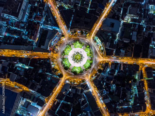 Beautiful roundabout intersection at night view. Aerial view of circle transportation in the city with colorful light. Drone view from night sky.