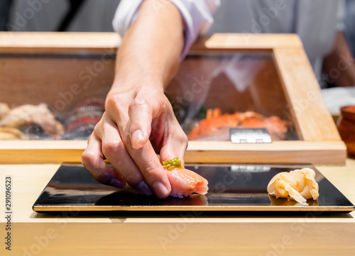Japanese Sushi Chef serve sushi by hand on the black shimmer plate. (Omakase sushi course) Selective focus on sushi.