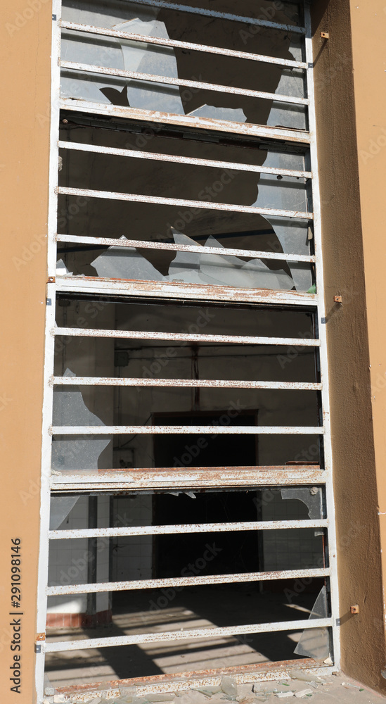 window with glass completely broken by vandals and metal bars