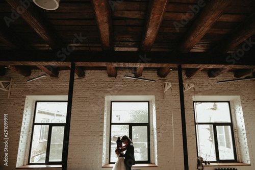 Bride and groom stand near the window. Interracial marriage. Asian bride and groom.