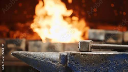 Hammer on anvil in forge on furnace with fire background in smithy workshop. photo