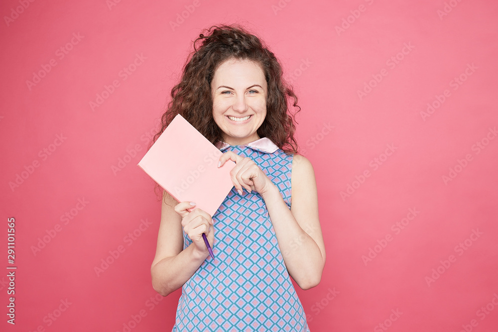 Education concept. Optimistic glad young Caucasian woman with pleased expression,charming smile, blue eyes holds textbooks and pen, rejoices learning new information, isolated on pink wall background Education concept. Optimistic glad young Caucasian woman with pleased expression,charming smile, blue eyes holds textbooks and pen, rejoices learning new information, isolated on pink wall background
