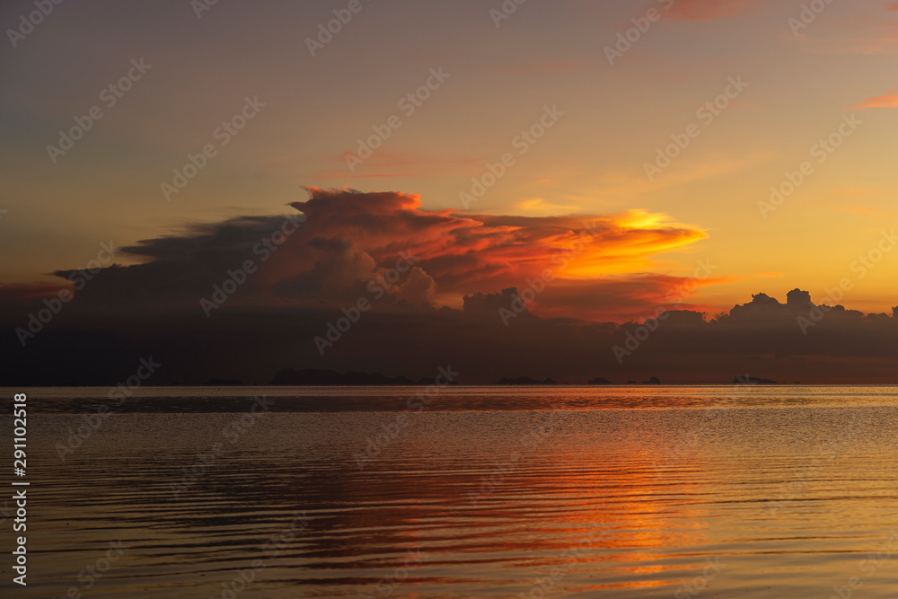 Naklejka premium Storm clouds during sunset.Colorful sunset over calm sea water near tropical beach. Summer vacation concept. Island Phangan, Thailand