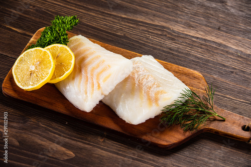 Fresh raw cod served on cutting board on wooden table