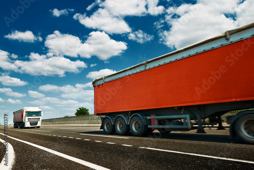 Red trucks is on highway - business, commercial, cargo transportation concept, clear and blank space on the side view