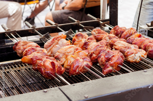 Cooking, appetizing delicious fresh grilled meat marinated on a barbecue rotating, preparing juicy greasy tasty meat on the grill, streetfood culture, bbq concept, closeup