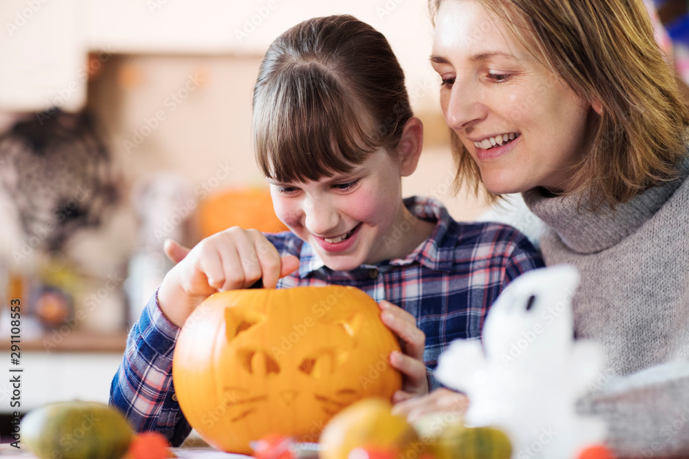Fototapeta premium Mother And Daughter Carving Halloween Lantern From Pumpkin At Home