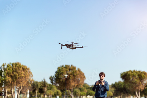 A man piloting a drone in the park in spring-summer time
