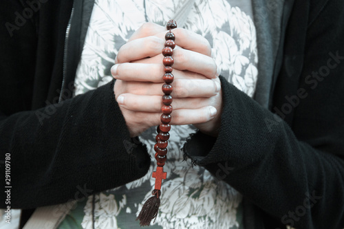 Hands folded for prayer, with monastic beads with a crucifix-cross clamped in them. Prayer, the hands of a Christian
