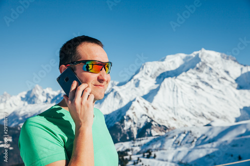Handsome young male taking a picture with his smartphone. Mont Blanc in the background.