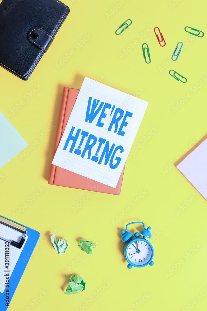 Obraz premium Text sign showing We Re Hiring. Business photo showcasing Advertising Employment Workforce Placement New Job Pile of empty papers with copy space on the table