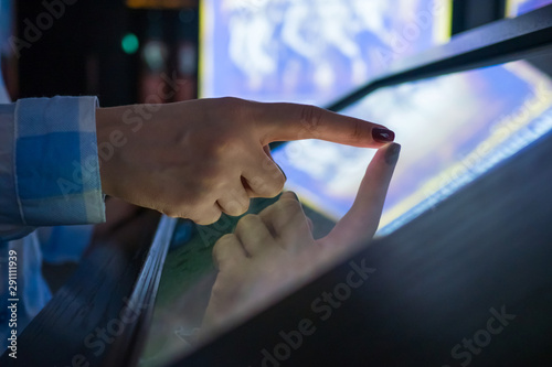 Woman using interactive touchscreen display of electronic multimedia kiosk at modern museum or exhibition. Education, learning and technology concept