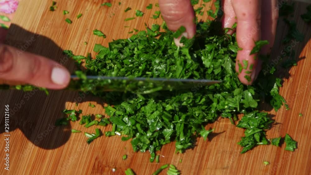 Chef chopping fresh parsley on a wooden board Chef chopping fresh parsley on a wooden board