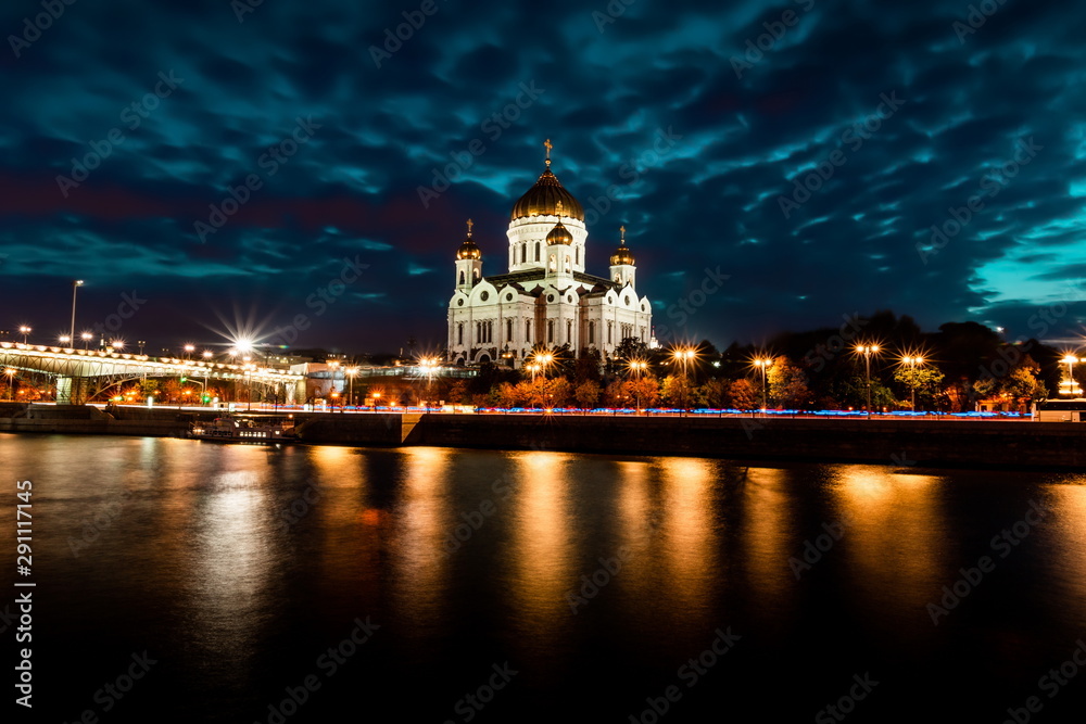 Illuminated Cathedral of Christ the Savior framed with old style street lights of Patriarchy Bridge at night.