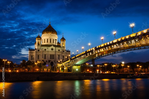 Illuminated Cathedral of Christ the Savior framed with old style street lights of Patriarchy Bridge at night.