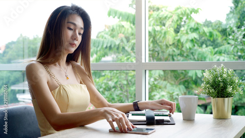 Young beautiful Asian woman enjoying a relaxing moment working and using mobile phone as mobile smart payment to pay for a coffee in the coffeeshop on a bright sunny day Free Download Young beautiful Asian woman enjoying a relaxing moment working and using mobile phone as mobile smart payment to pay for a coffee in the coffeeshop on a bright sunny day - GFXLoad