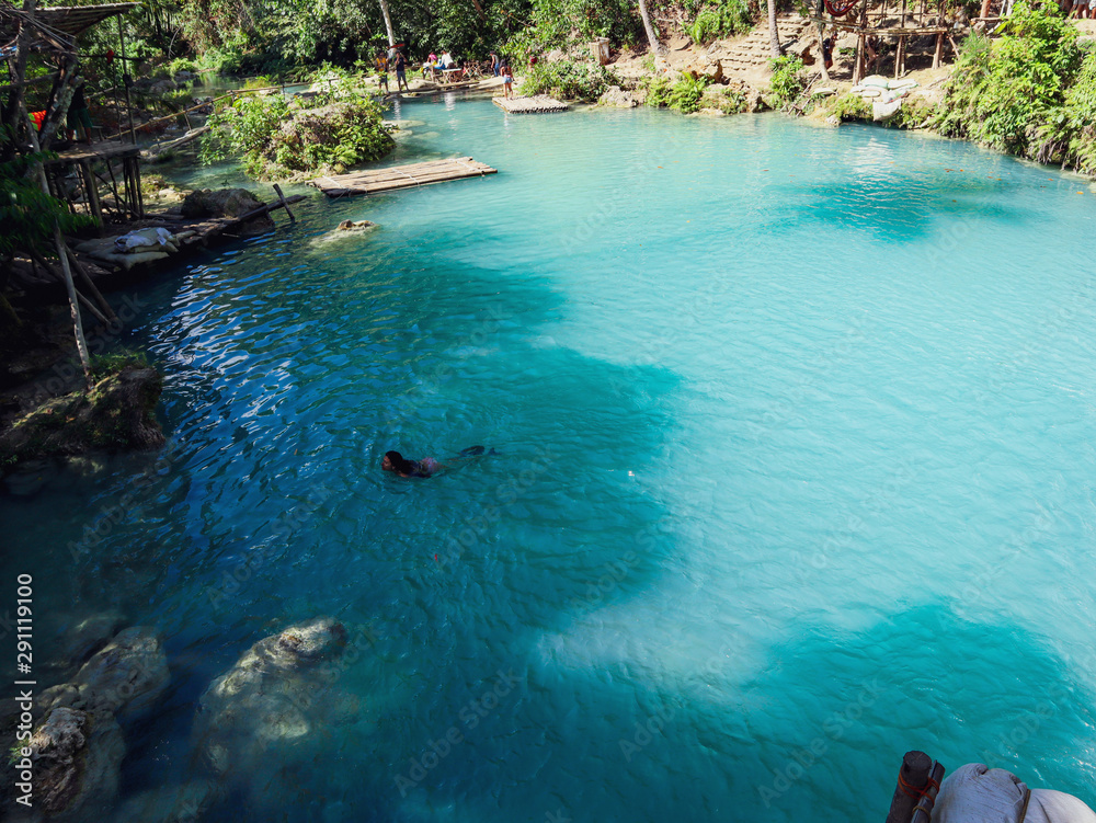 woman swimming freely at turquoise water of cambugahay waterfalls in Siquijor Island in Philippines