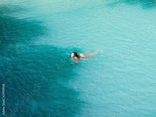 woman swimming freely at turquoise water of cambugahay waterfalls in Siquijor Island in Philippines