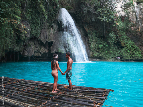 travel couple alone on the bamboo raft in front of the waterfall with turquoise water in Kawasan Falls in Cebu Island, Philippines © Alohadunya
