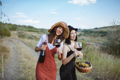 Two happy girls with two glasses of wine in their hands.