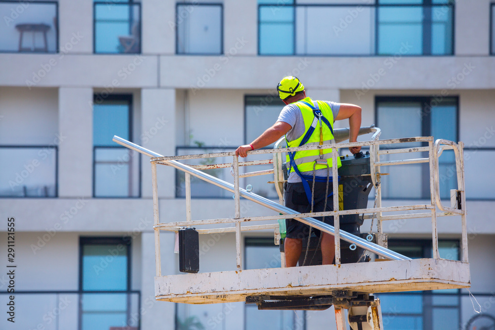 Professional installation work on a construction building site. Assemblers perform high-altitude installation works on the telescopic  boom lifts platforms. Installation of beams.