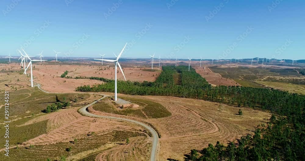 Aerial view with a drone of wind turbines in fields under the blue sky. This is a wind farm which produce sustainable energy, perfect for environment - environmental & ecological concept Aerial view with a drone of wind turbines in fields under the blue sky. This is a wind farm which produce sustainable energy, perfect for environment - environmental & ecological concept