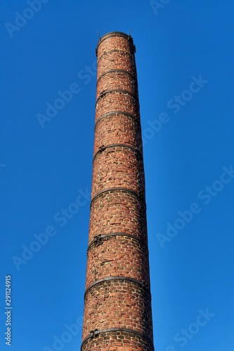 Old brick smokestack in front of blue sky.
