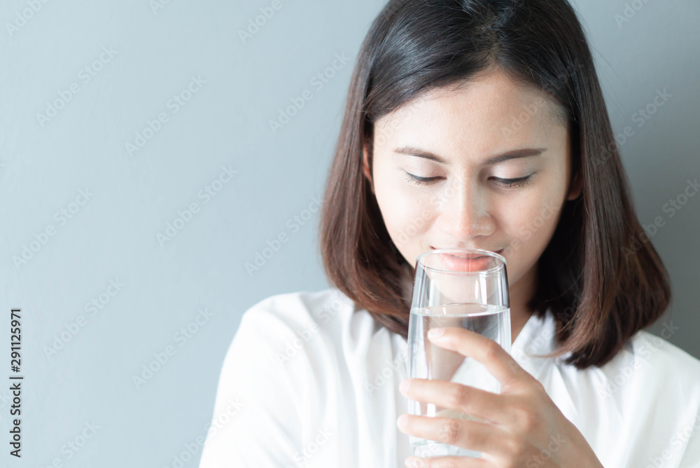 Close up woman drinking pure water from glass with light in the morning, Selective focus Close up woman drinking pure water from glass with light in the morning, Selective focus