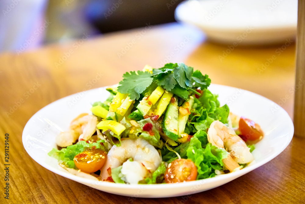 Salad with shrimp, avocado, lettuce and tomatoes in the Asian style is on the plate. Salad with shrimp, avocado, lettuce and tomatoes in the Asian style is on the plate.