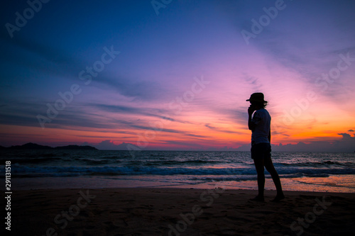 Silhouette of The girl is walking happily Use the phone at the beach during the sunset and her enjoying freedom feeling happy at sunset  © Morakot