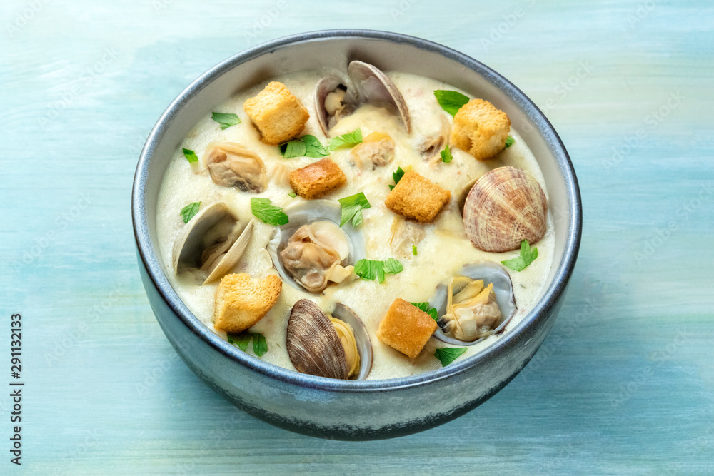 Clam chowder, decorated with fresh parsley and croutons, on a blue background Clam chowder, decorated with fresh parsley and croutons, on a blue background