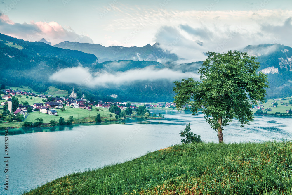 Foggy summer scene of Lungerersee lake. Bright morning view of Swiss Alps, Lungern village location, Switzerland, Europe. Traveling concept background. Instagram filter toned.