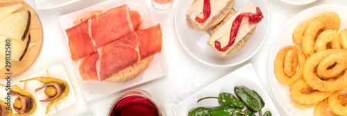 A panorama of Spanish tapas. Jamon, squid rings, cheese, gildas and other snacks, shot from the top on a white background photo