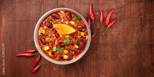 Foto Chili con carne with chilli peppers and a nacho chip, overhead panoramic shot on