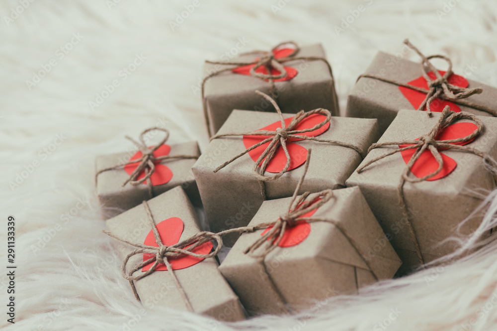 Set of gift boxes wrapped in craft paper and tie hemp string. With cardboard hearts. White fur background. Set of gift boxes wrapped in craft paper and tie hemp string. With cardboard hearts. White fur background.