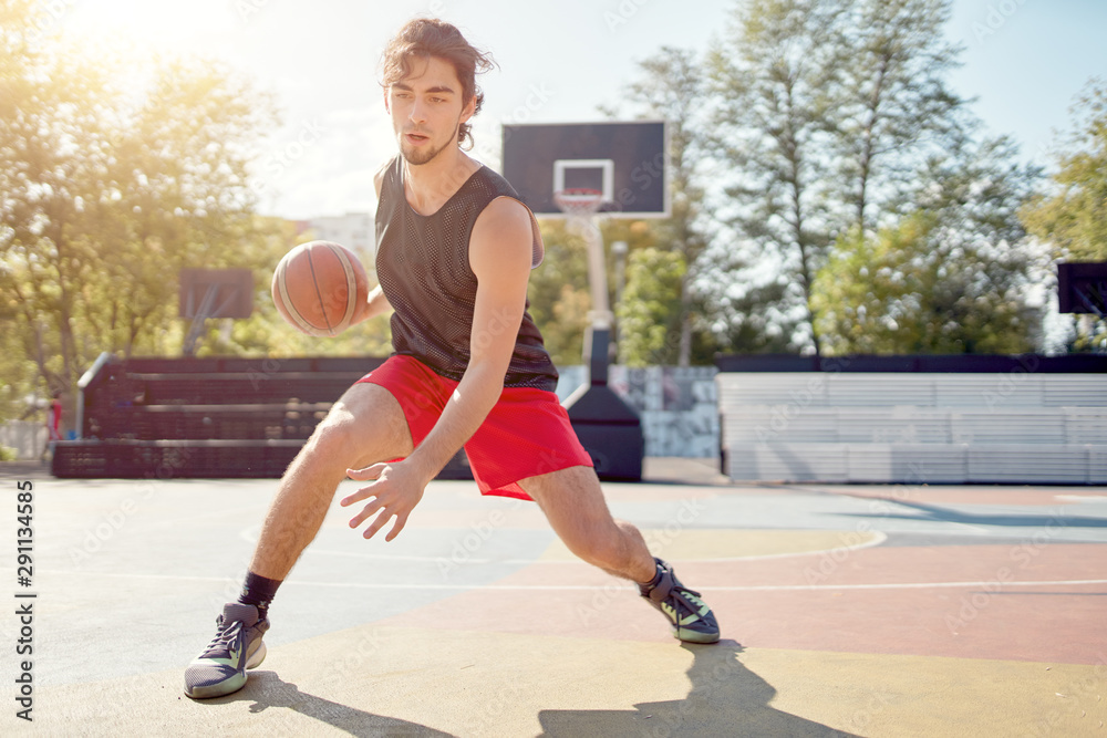 Obraz premium Photo of athlete in blue T-shirt playing basketball on playground
