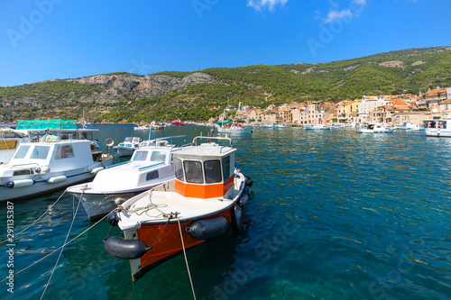 View on port on Adriatic Sea, moored boats and old buildings, island Vis, Komiza, Croatia