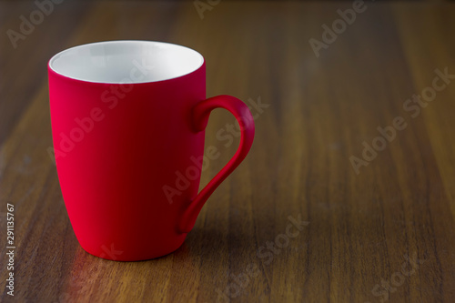 empty bright red porcelain mug close-up on a wooden table